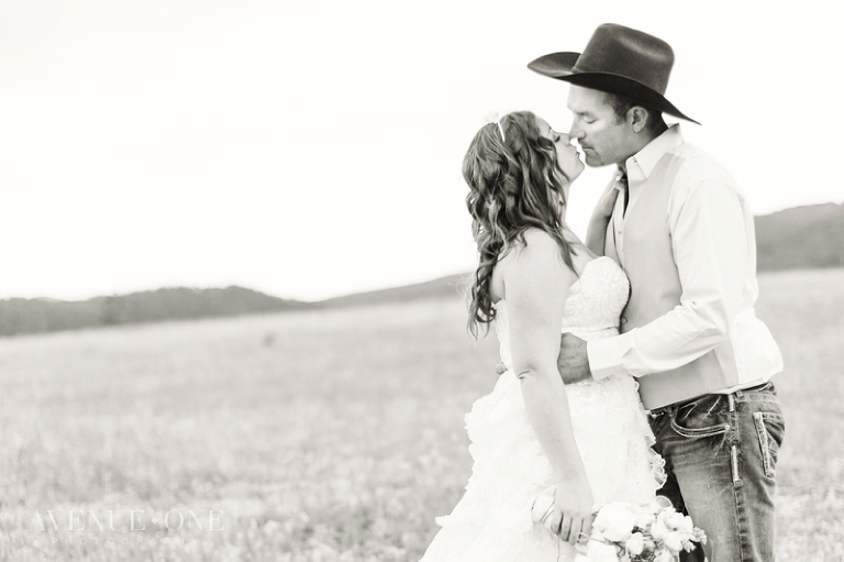 bride and groom kissing in field
