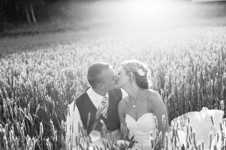 bride and groom sitting in field of grass