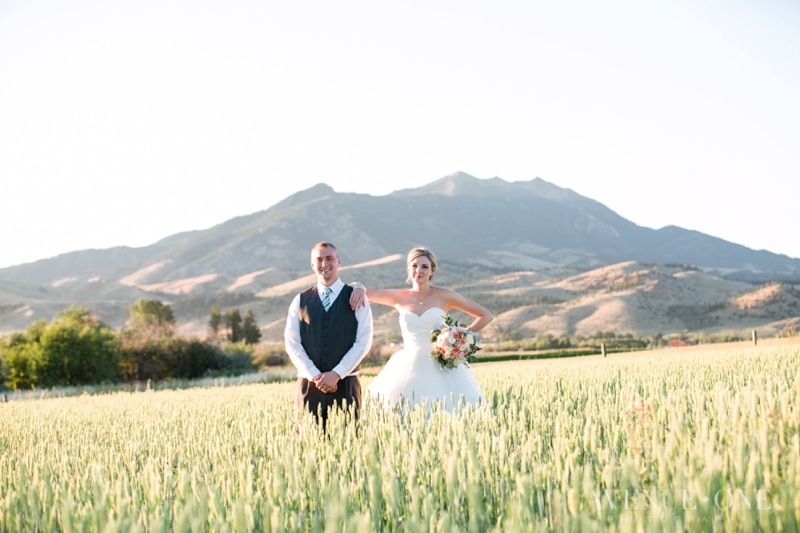 bride with arm on grooms shoulder in field