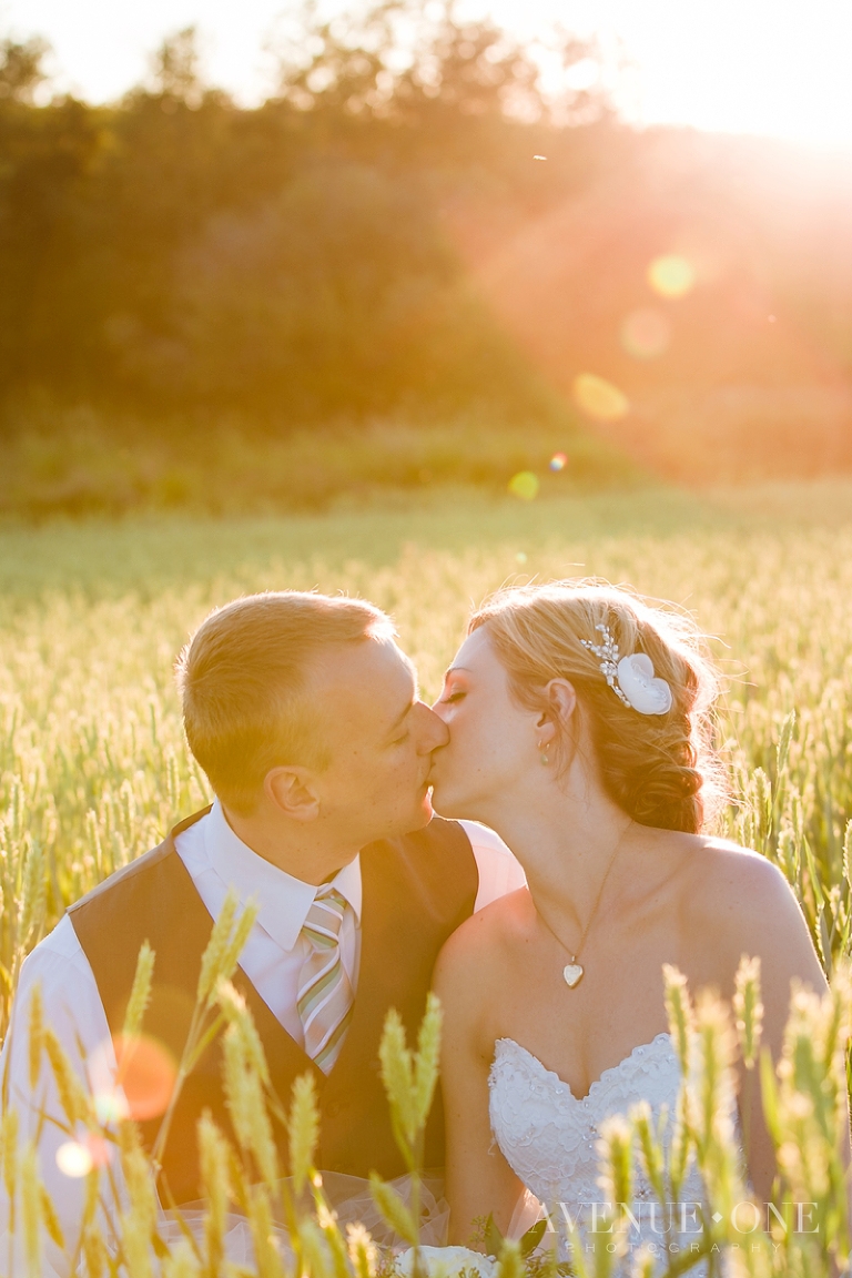 bride and groom in field with sun flare