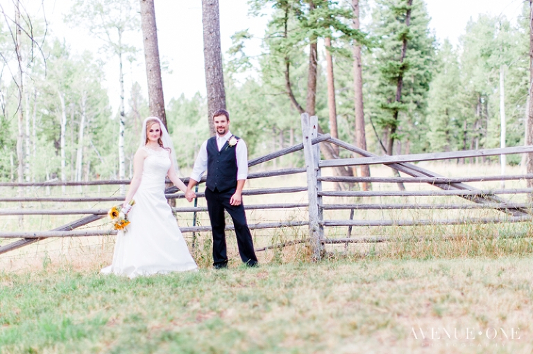 Bride and groom holding hands by fence