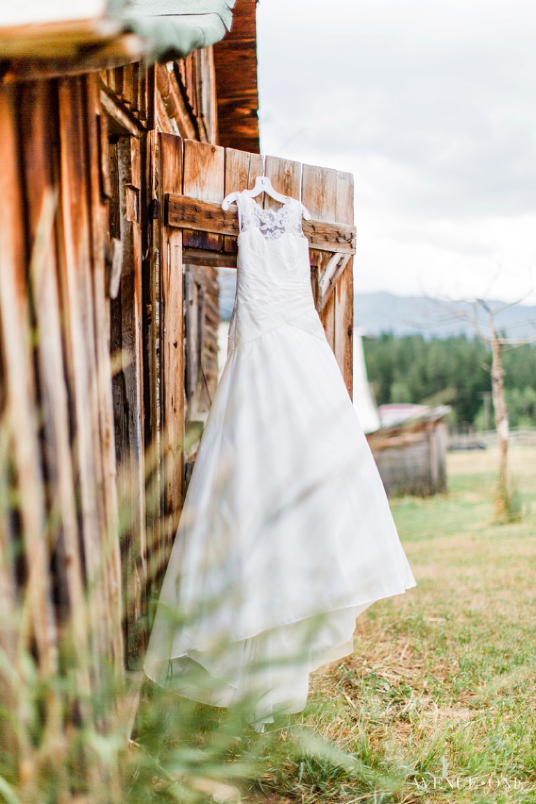 lace wedding dress hanging on rustic wood door