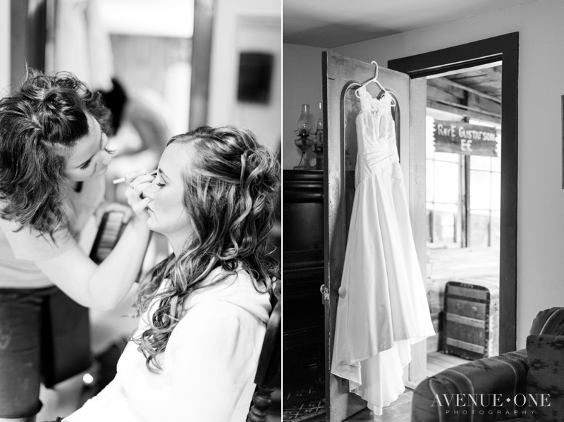 bride putting makeup on with dress hanging in background