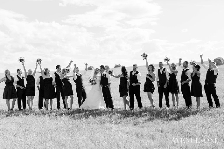 bridal party cheering while bride and groom kiss