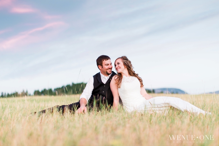 bride and groom sitting in field of grass